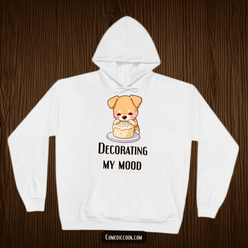 Funny hoodie featuring a dog concentrating on decorating a small cake with sprinkles, perfect for cozy, humorous wear for bakers.
